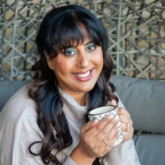 Portrait of Nikita Thakrar smiling outdoors against a natural textured background