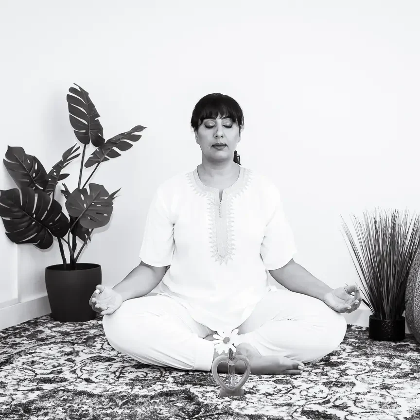 Black and white portrait of a woman standing beside a leafy plant in a minimalist space