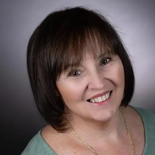 Portrait of a smiling woman Robin with short brown hair against a neutral background